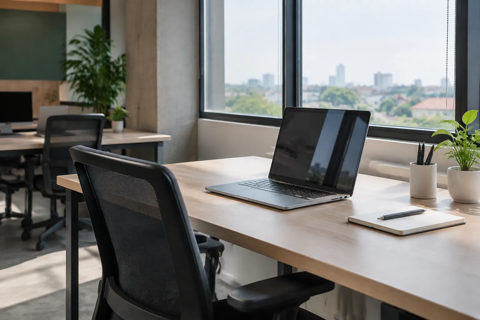Meja kerja dan laptop menghadap bukaan kantor