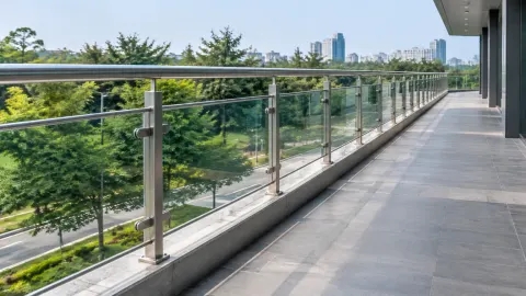 Railing kaca panjang di tepi balkon menghadap pepohonan