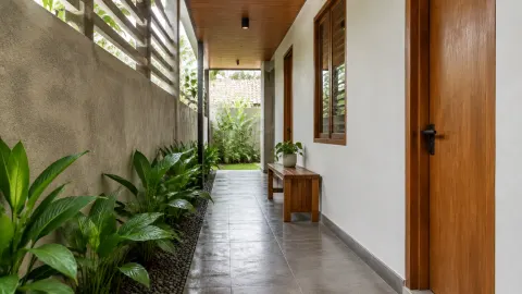 Lorong rumah tropis di samping taman sempit dan dinding berjalusi
