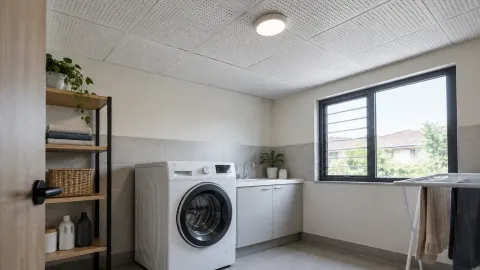 Ruang laundry dengan mesin cuci, meja kerja, dan plafon