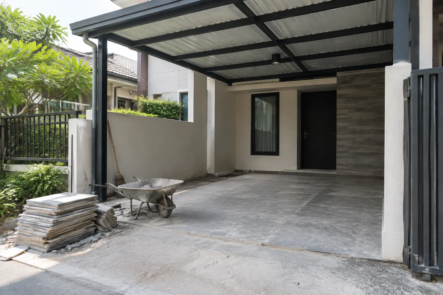 Carport kosong beratap dengan tumpukan material di sisi depan