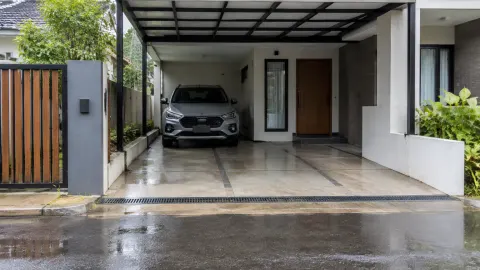 Carport beratap dengan saluran air di depan kendaraan
