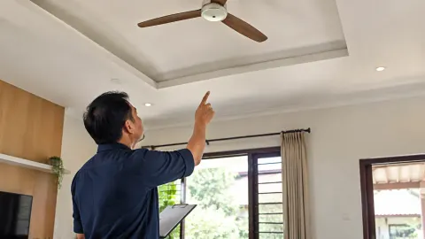 Seseorang meninjau kipas plafon di ruang rumah