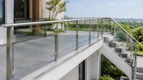 Railing kaca mengelilingi teras tinggi dan tangga luar