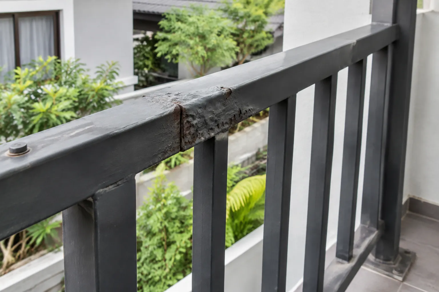 Cat mengelupas dan karat terlihat pada sambungan pagar balkon