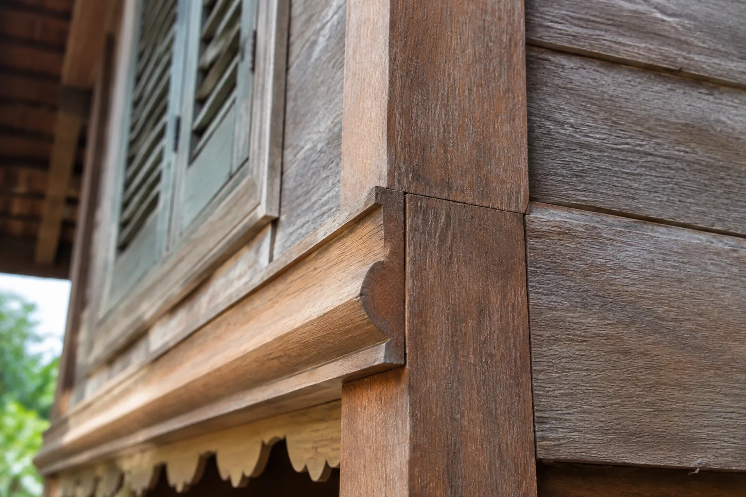 Detail trim ukir kayu di bawah jendela rumah tradisional