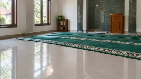 Mushola dengan karpet hijau dan lantai batu terang