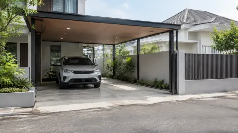 Carport beratap lebar dengan sisi terbuka ke halaman