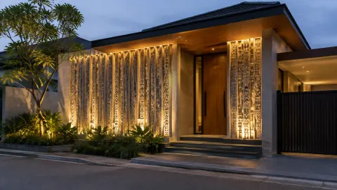 Fasad rumah dengan panel ornamen bercahaya pada malam hari