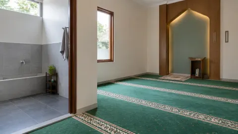 Musala dengan karpet hijau dan dinding depan beraksen