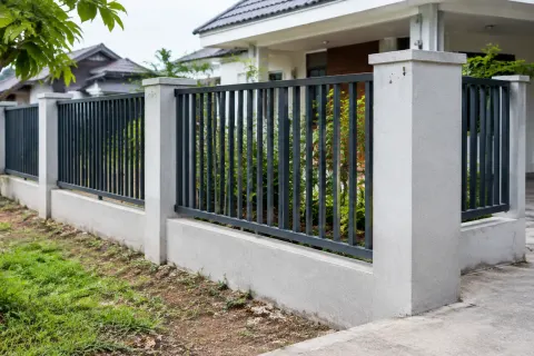 Pagar logam dengan tiang beton di depan rumah