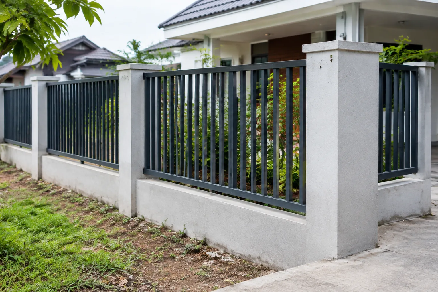 Pagar logam dengan tiang beton di depan rumah