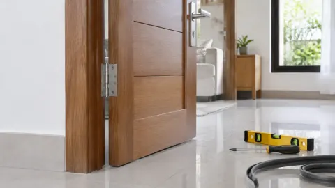 Pintu kayu terbuka dengan ambang dan lantai keramik terlihat
