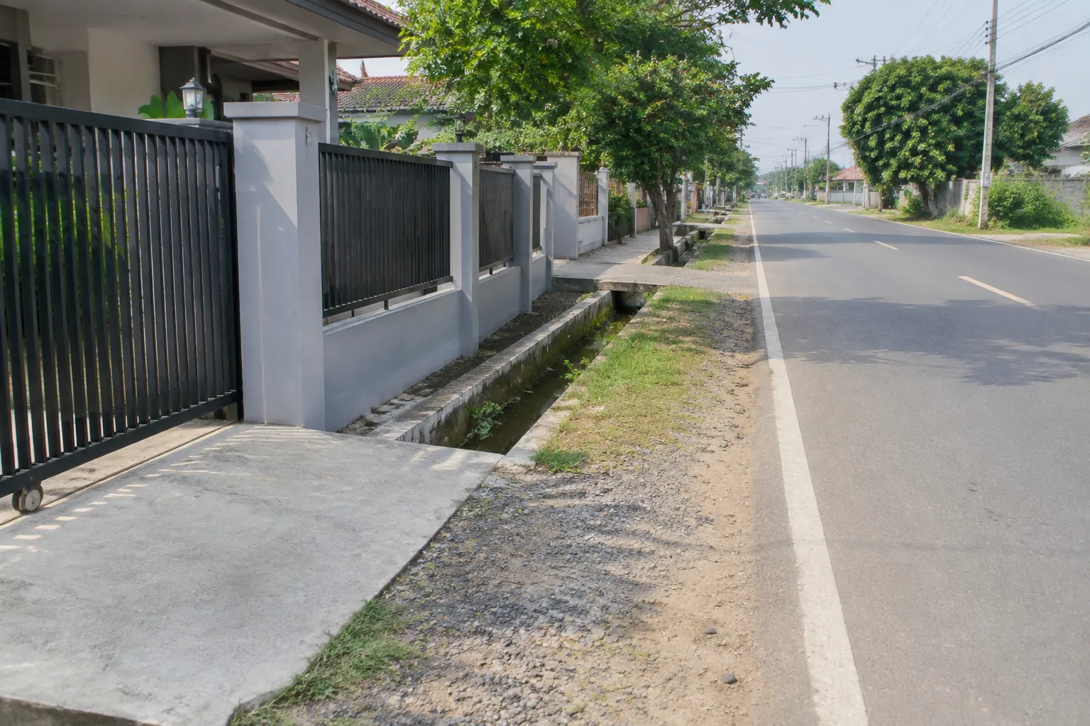 Gerbang rumah berbatasan dengan trotoar dan jalan