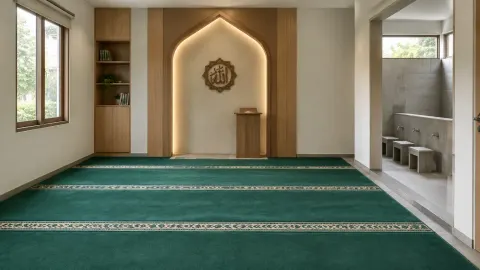 Musala dengan karpet salat hijau dan relung dinding bercahaya
