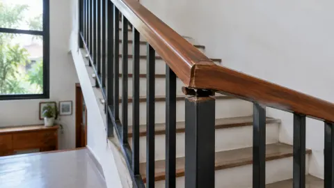 Railing tangga dengan pegangan kayu dan batang logam