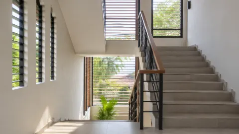 Tangga rumah dengan jendela dan kisi pada dinding samping