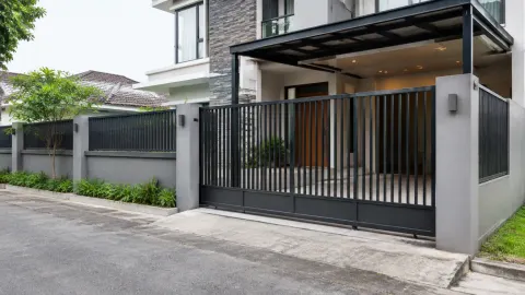 Gerbang dan pagar logam berwarna gelap di depan rumah