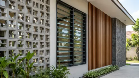 Fasad rumah dengan kisi beton dan jendela jalusi