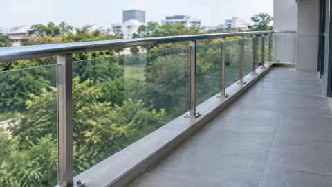 Railing kaca pada balkon tinggi menghadap pepohonan