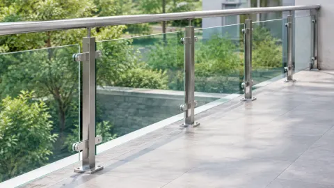 Railing kaca dengan tiang logam di tepi balkon