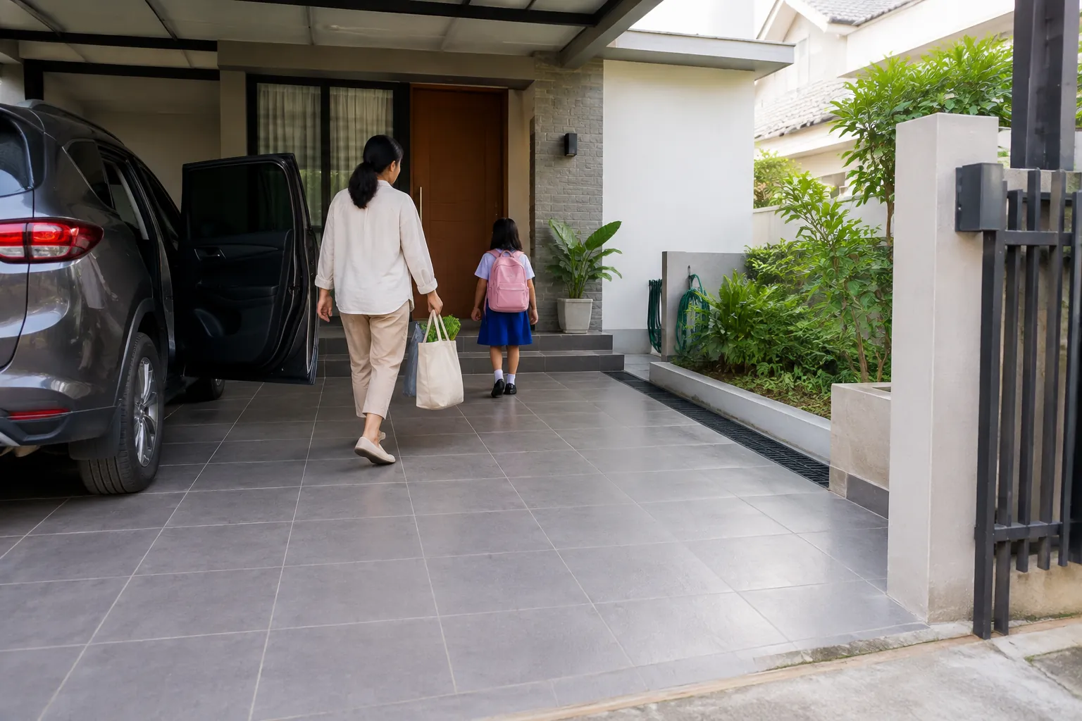 Orang dewasa dan anak berjalan melintasi lantai carport