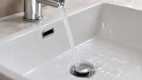 Lubang overflow dan saluran bawah pada wastafel putih
