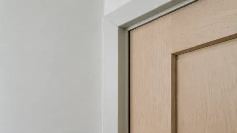 Trim putih sederhana membingkai pintu kayu