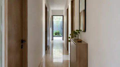 Lorong rumah sempit dengan kabinet rendah dan cermin