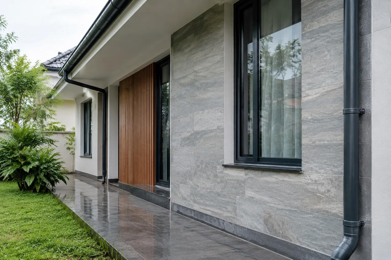 Fasad rumah dengan pelapis abu-abu dan pipa air hujan