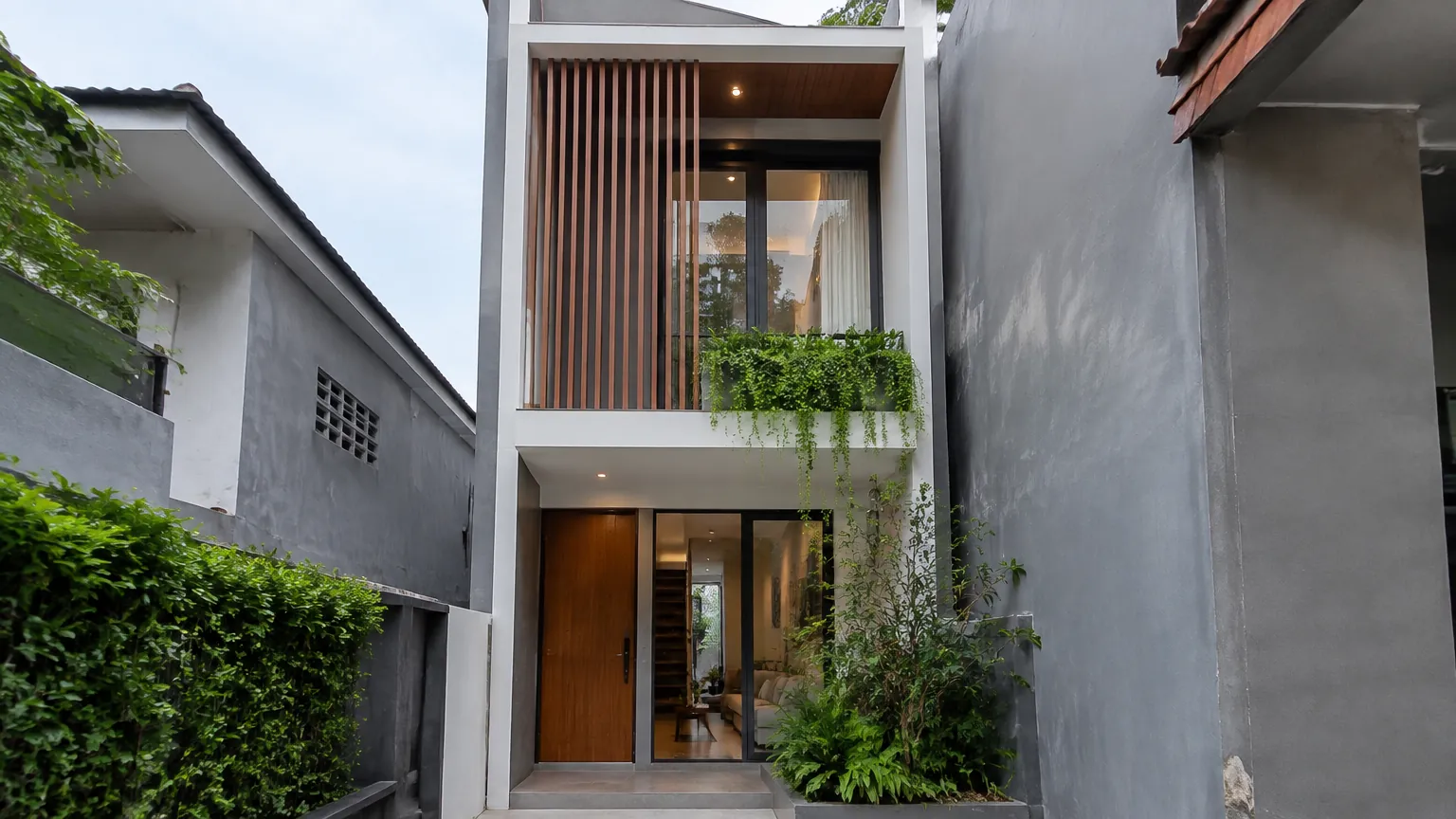 Fasad rumah sempit dengan panel vertikal dan jendela