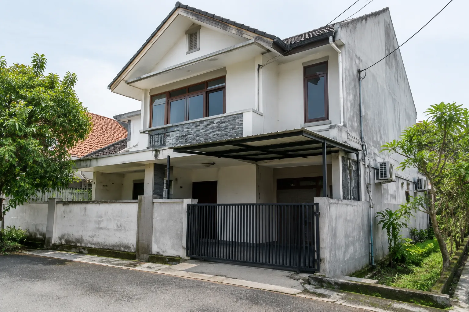 Fasad rumah lama dengan dinding kusam dan kanopi