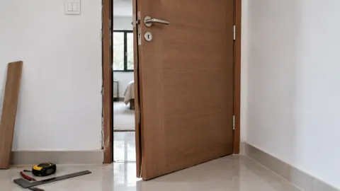 Pintu kayu terpasang di ruang rumah dengan alat kerja di lantai