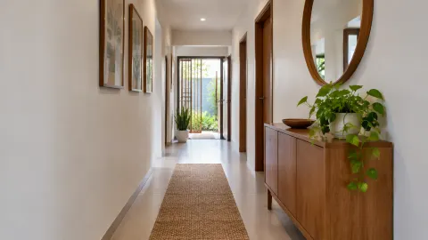 Lorong rumah terang dengan lemari kecil dan tanaman