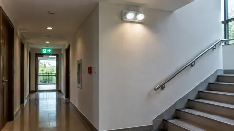 Lorong menuju pintu keluar dengan lampu darurat di dekat tangga