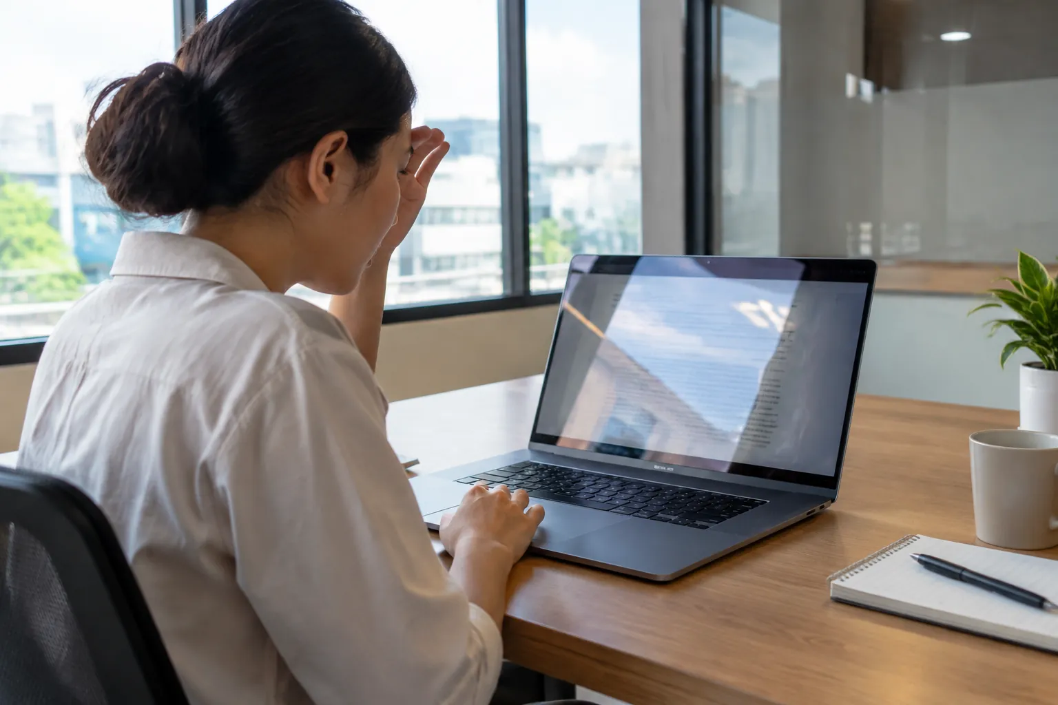 Seseorang bekerja di laptop dekat jendela kantor