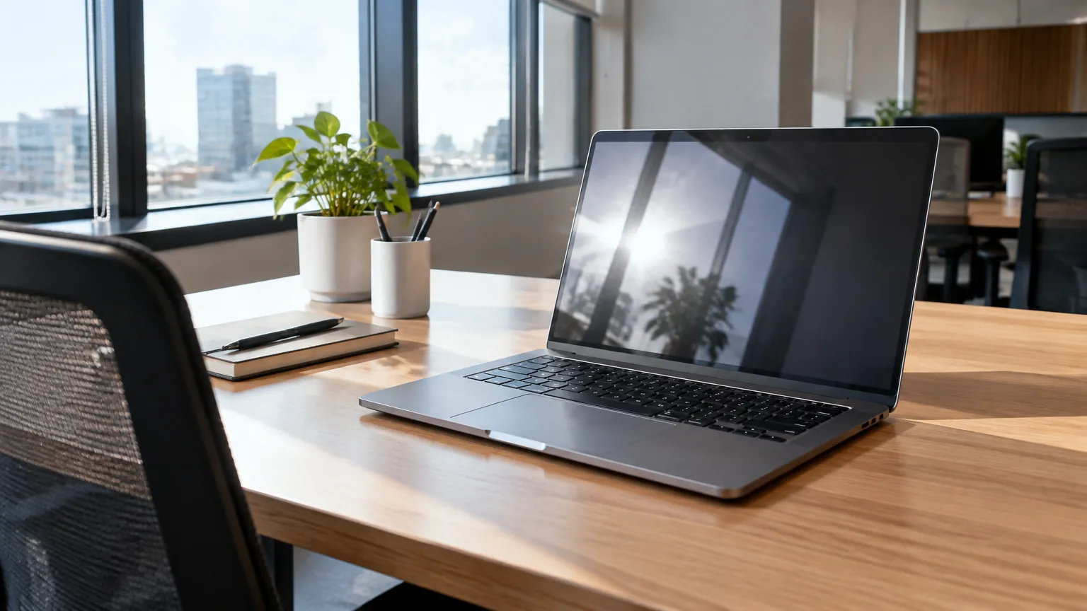 Laptop pada meja kerja di dekat jendela kantor