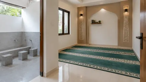 Musala dengan karpet hijau dan area wudu di samping