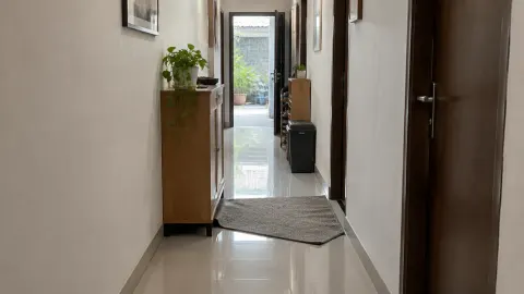 Lorong rumah sempit dengan beberapa pintu dan permukaan lantai licin mengilap