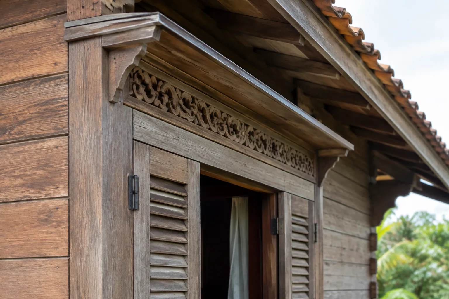 Trim ukir kayu di tepi atap dan jendela rumah tradisional