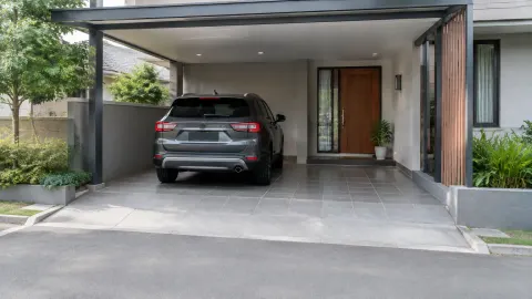 Mobil terparkir di carport rumah di samping pintu masuk