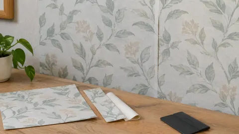 Wallpaper bermotif daun dengan sampel di atas meja