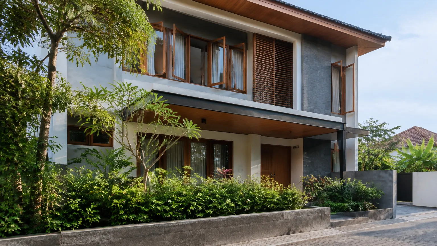 Rumah dua lantai dengan bukaan jendela dan peneduh fasad
