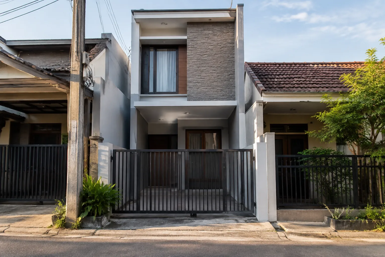 Rumah sempit dengan fasad bertekstur dan pagar depan