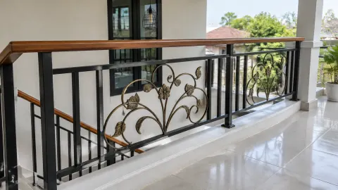 Railing balkon besi dengan ornamen lengkung dan pegangan kayu