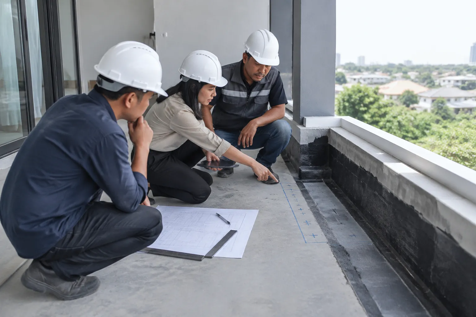 Pekerja meninjau tepi lapisan kedap air pada balkon sebelum dudukan pagar dipasang