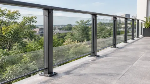 Railing kaca dengan tiang logam di tepi balkon luar