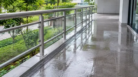 Air menggenang di lantai balkon dekat railing kaca