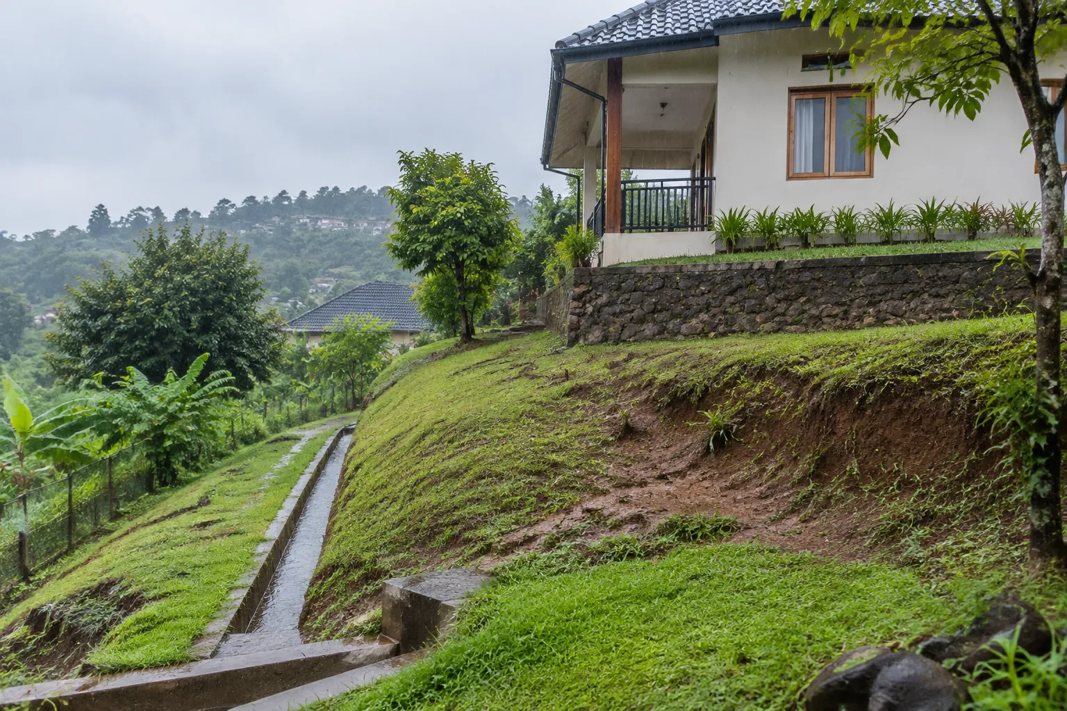 Saluran mengikuti kaki lereng di samping rumah