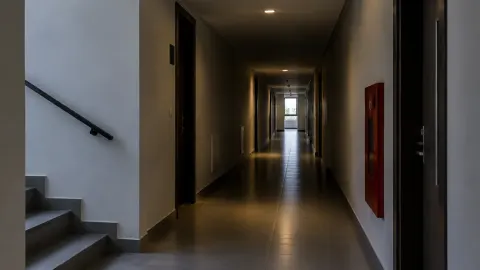Lorong rumah panjang dengan lampu plafon yang redup